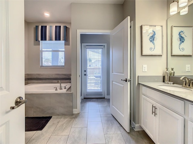 bathroom with tiled tub and vanity