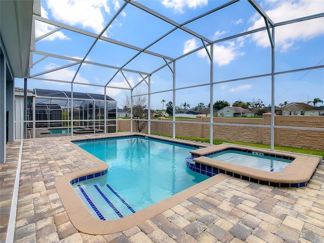 view of pool featuring glass enclosure, an in ground hot tub, and a patio area