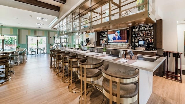 bar with beamed ceiling and light hardwood / wood-style flooring