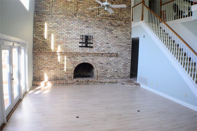 unfurnished living room featuring a high ceiling, hardwood / wood-style flooring, french doors, and a healthy amount of sunlight