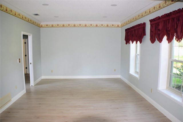 spare room featuring a healthy amount of sunlight, light hardwood / wood-style floors, and crown molding