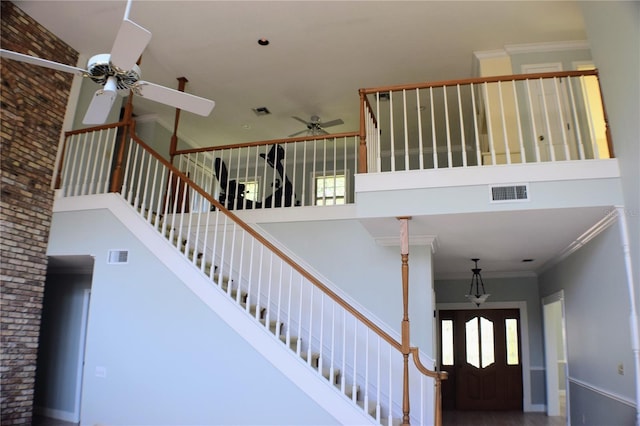 stairway featuring ceiling fan, a towering ceiling, and ornamental molding