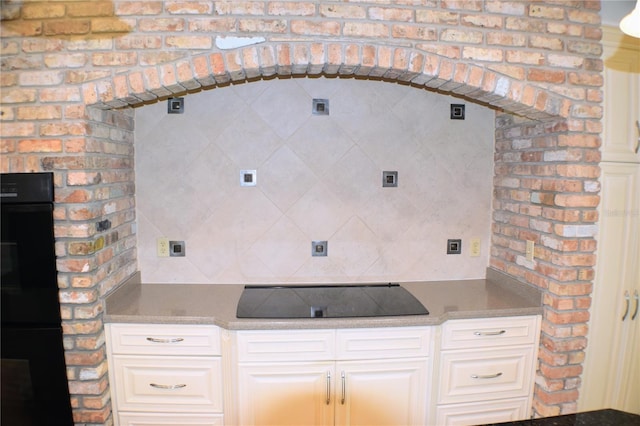 interior space featuring black electric cooktop and brick wall