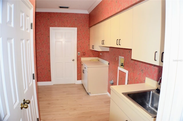 clothes washing area with cabinets, hookup for a washing machine, light wood-type flooring, crown molding, and sink