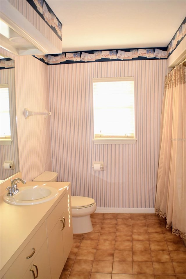 bathroom featuring toilet, vanity, tile patterned floors, and a healthy amount of sunlight