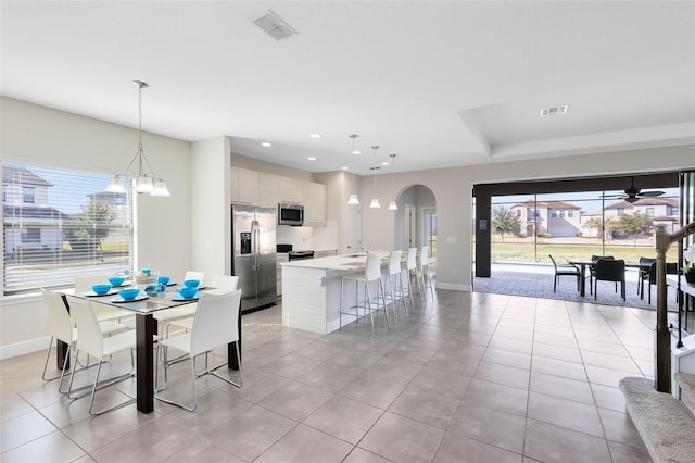 tiled dining space with ceiling fan with notable chandelier and sink