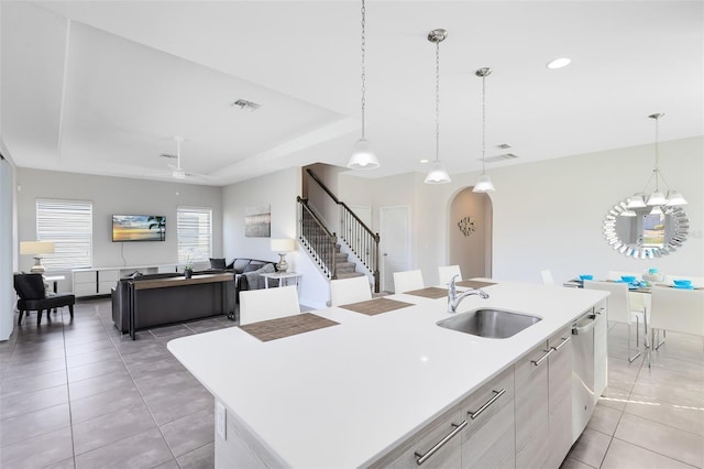 kitchen with a center island with sink, pendant lighting, ceiling fan with notable chandelier, and sink