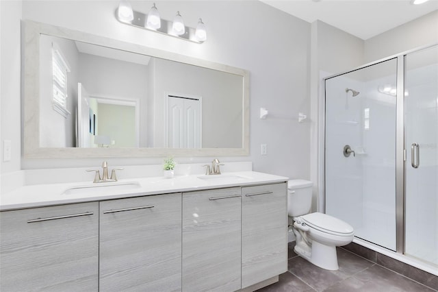 bathroom featuring tile patterned flooring, vanity, toilet, and a shower with door