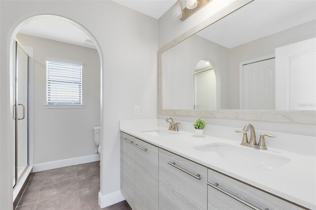 bathroom with tile patterned floors, vanity, toilet, and a shower with shower door