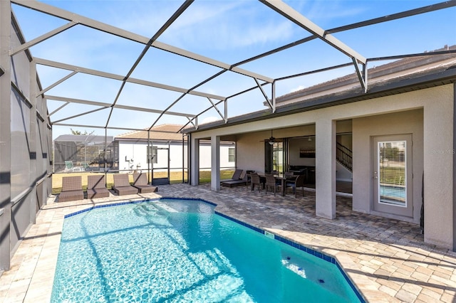 view of swimming pool with glass enclosure, ceiling fan, and a patio area