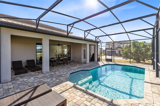 view of pool with glass enclosure, ceiling fan, and a patio area