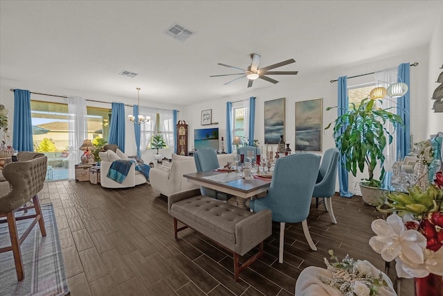 dining space with ceiling fan with notable chandelier and dark wood-type flooring