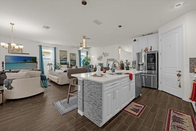 kitchen featuring appliances with stainless steel finishes, decorative light fixtures, white cabinets, dark hardwood / wood-style floors, and an island with sink