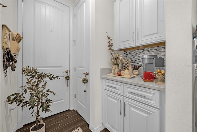 interior space with backsplash, dark hardwood / wood-style flooring, and white cabinets