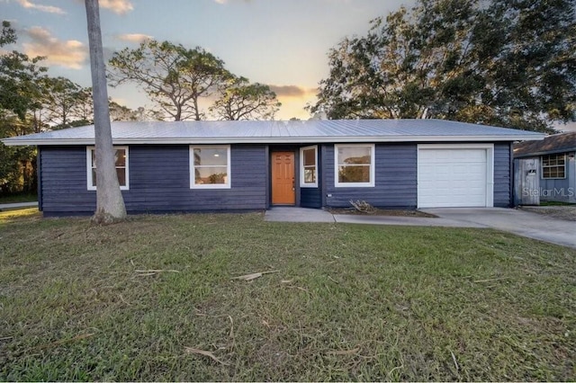 ranch-style home featuring a lawn and a garage