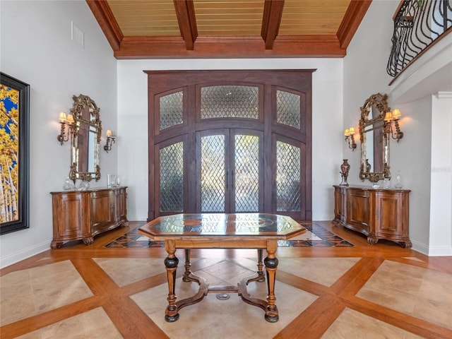 entryway with french doors, a towering ceiling, wooden ceiling, and ornamental molding