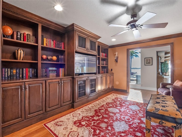 living room featuring crown molding, light hardwood / wood-style flooring, and ceiling fan