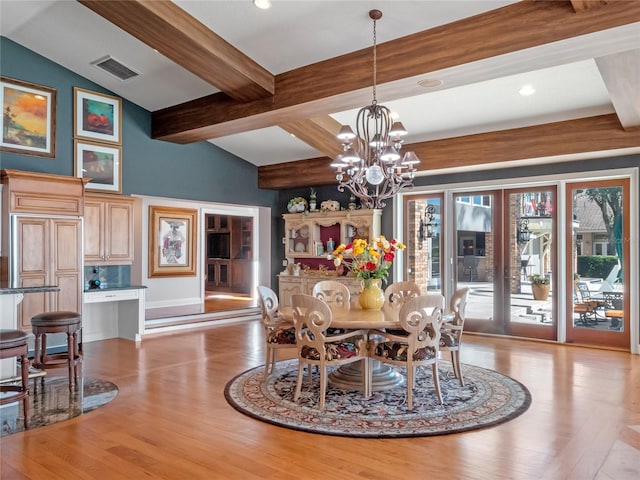 dining space featuring light hardwood / wood-style flooring, lofted ceiling with beams, and a notable chandelier