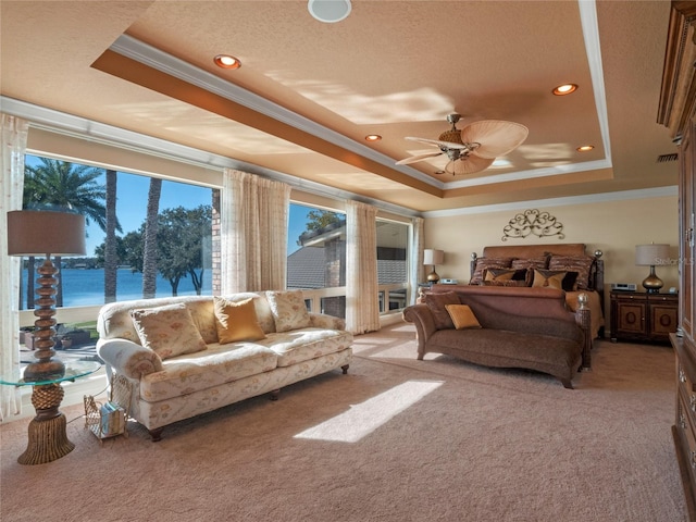 bedroom with a tray ceiling, ceiling fan, a water view, and light colored carpet