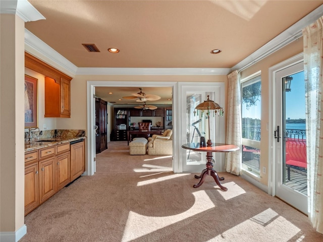 interior space with ceiling fan, sink, light stone counters, crown molding, and light carpet