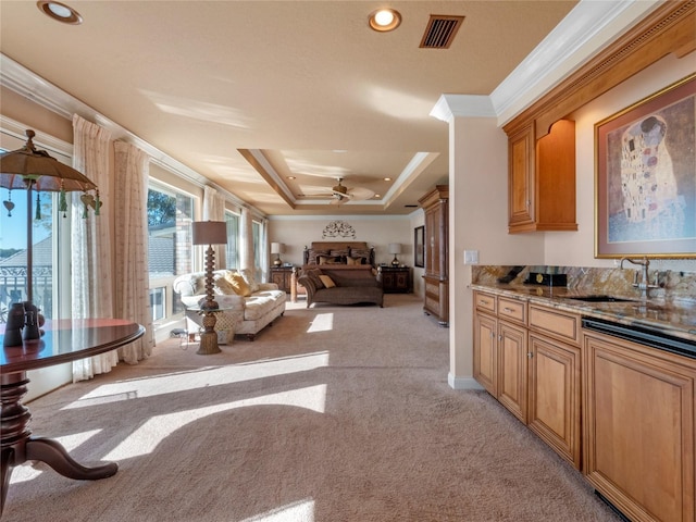 kitchen featuring light carpet, sink, ceiling fan, ornamental molding, and a tray ceiling