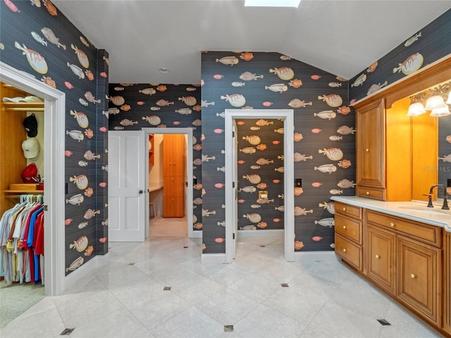 bathroom featuring vaulted ceiling with skylight and vanity