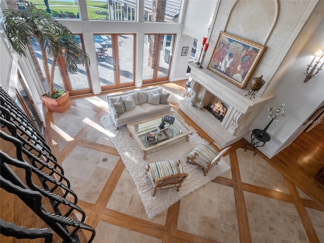 living room with a high ceiling, french doors, and a tiled fireplace