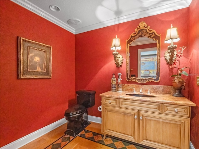 bathroom featuring toilet, vanity, wood-type flooring, and ornamental molding