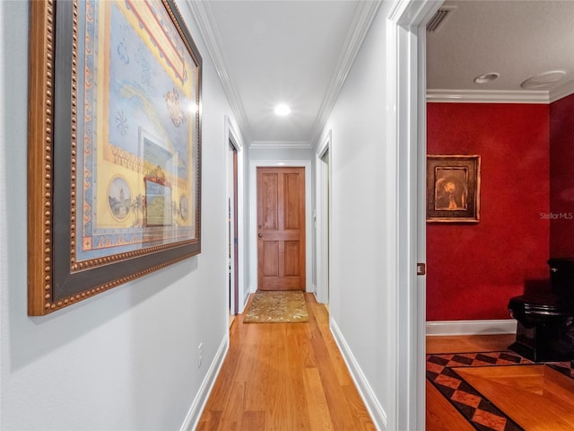 corridor with ornamental molding and light hardwood / wood-style flooring