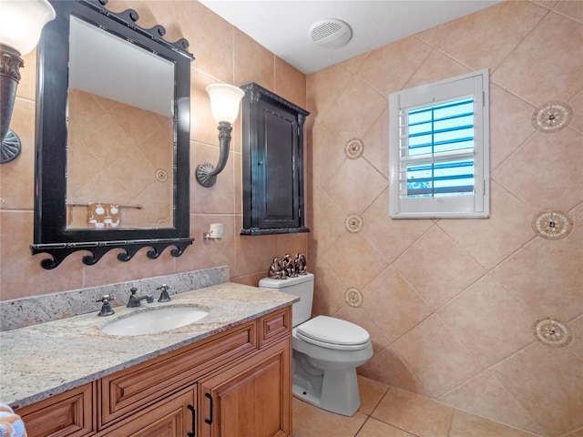 bathroom with tile patterned floors, vanity, toilet, and tile walls