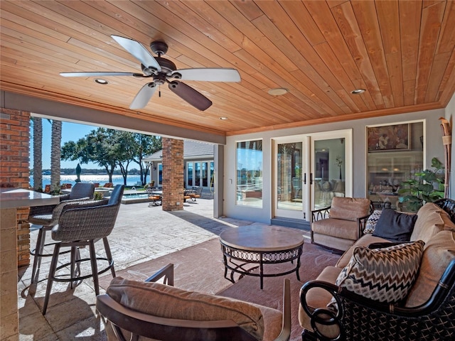 view of patio / terrace featuring ceiling fan, a water view, and exterior bar