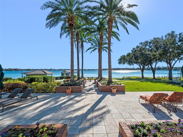 view of community with a patio, a water view, and a lawn