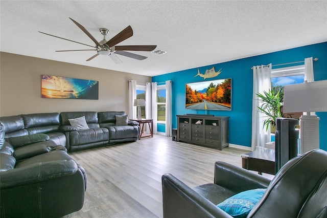 living room featuring ceiling fan, light hardwood / wood-style floors, and a textured ceiling