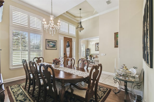 dining space with ornamental molding, light hardwood / wood-style floors, a high ceiling, and an inviting chandelier