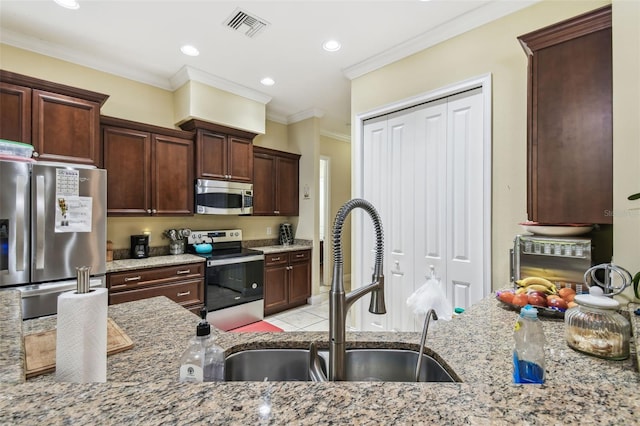 kitchen with light stone countertops, appliances with stainless steel finishes, ornamental molding, dark brown cabinets, and sink