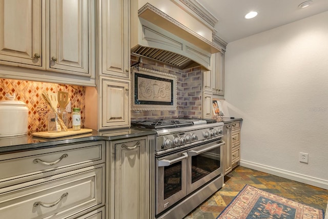 kitchen with double oven range, tasteful backsplash, cream cabinets, and custom exhaust hood