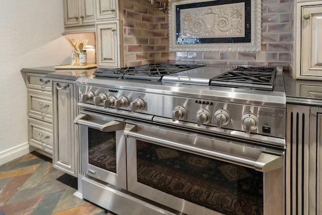 room details featuring cream cabinetry, double oven range, and backsplash