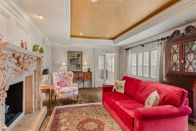 living room featuring wood-type flooring, a tray ceiling, a high end fireplace, and crown molding