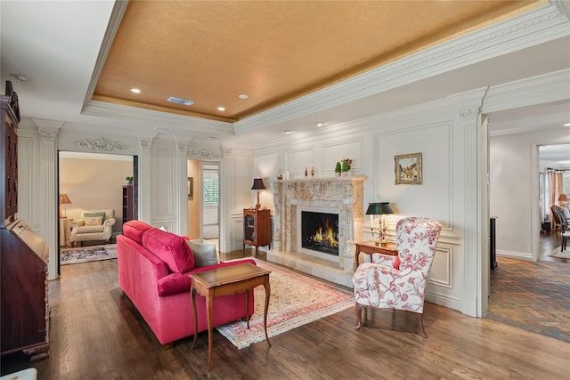 living room with a tray ceiling, dark hardwood / wood-style floors, crown molding, and a premium fireplace