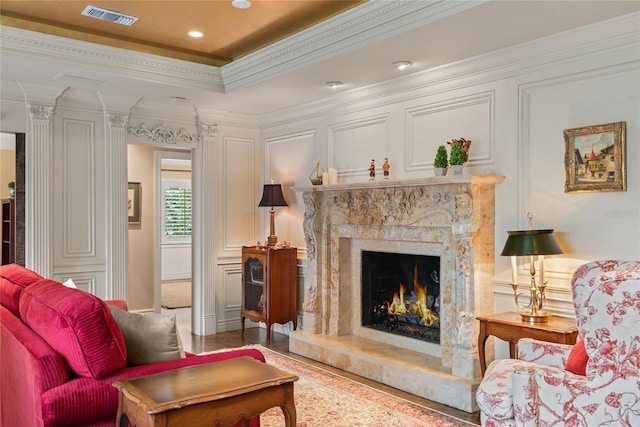 sitting room with a raised ceiling, ornamental molding, and a premium fireplace