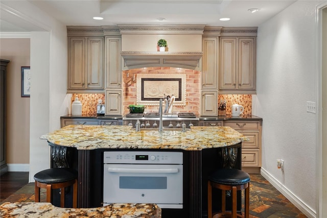 kitchen with tasteful backsplash, white oven, light stone countertops, and a kitchen breakfast bar