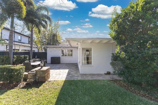 rear view of property featuring a lawn, an outdoor living space, and a patio