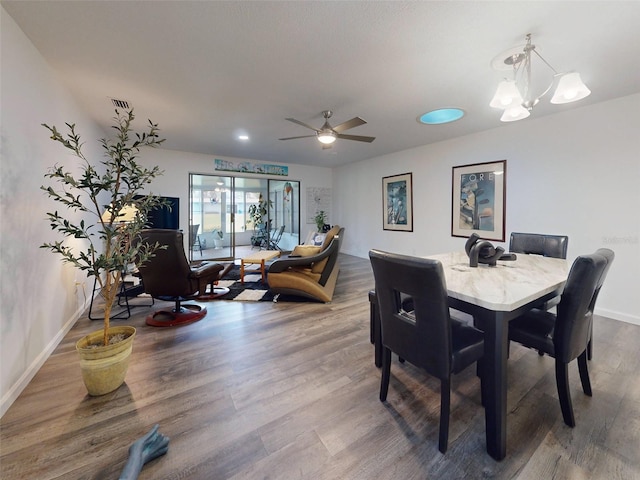 dining area with wood-type flooring and ceiling fan with notable chandelier