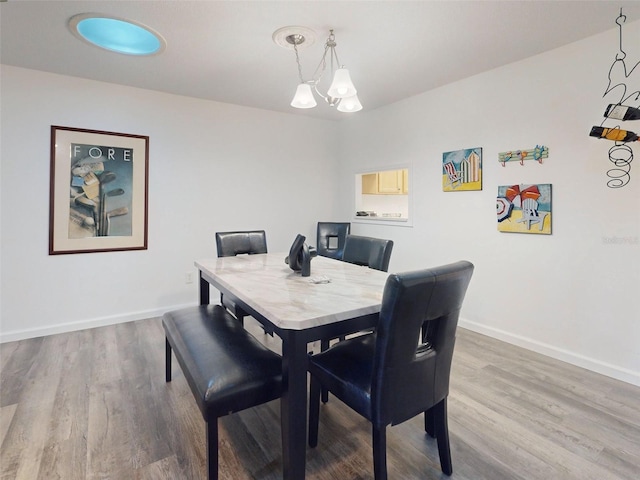 dining space with wood-type flooring and an inviting chandelier