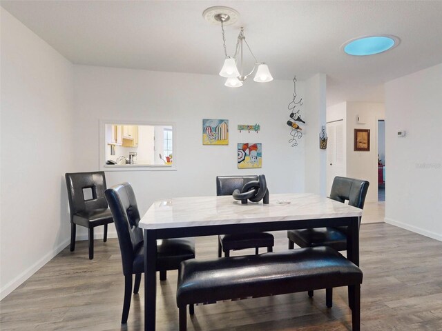 dining room with wood-type flooring and a notable chandelier