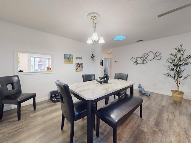 dining area featuring wood-type flooring and an inviting chandelier