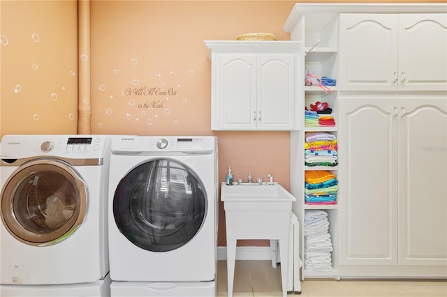 washroom with washing machine and dryer, light tile patterned floors, and cabinets