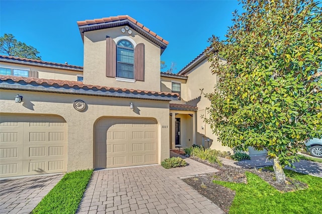 8169 Roseville Rd, Davenport, FL 33896 - view of front facade featuring stucco siding, a tile roof, decorative driveway, and an attached garage