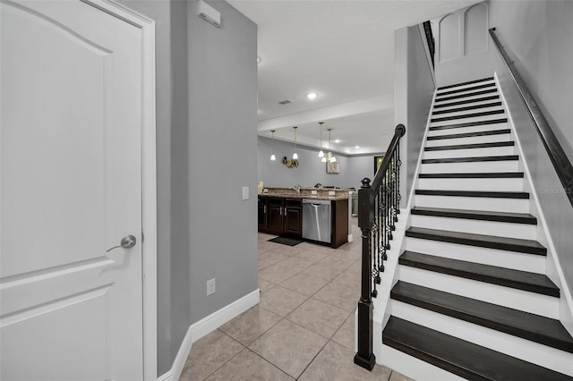 stairway featuring tile patterned flooring, sink, and a chandelier