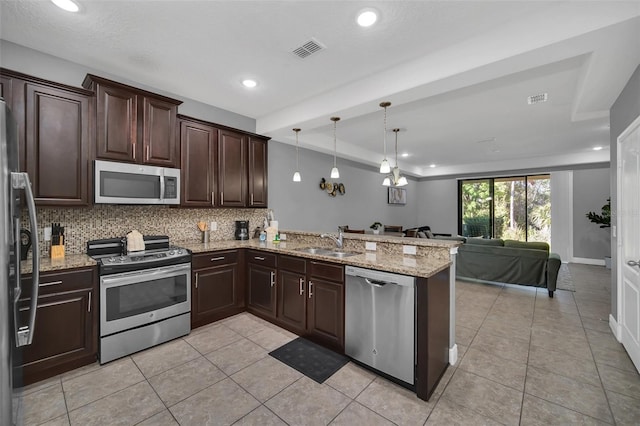 kitchen featuring sink, backsplash, kitchen peninsula, pendant lighting, and appliances with stainless steel finishes